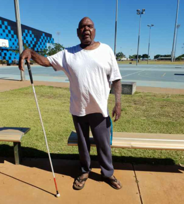 David standing with his cane in an outdoor area