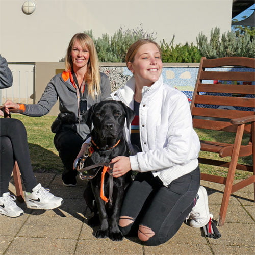 Tegan with black labrador Loui and trainer Katie in background