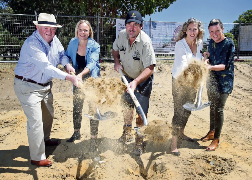 Five people involved in the project including architect Lisa Halton, lift up spades with soil on them.