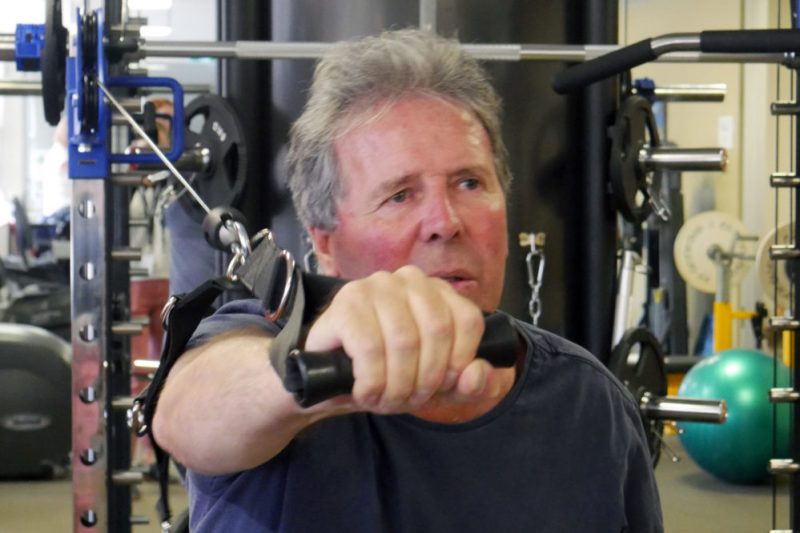 John pulls a weight forward working his shoulder muscles 