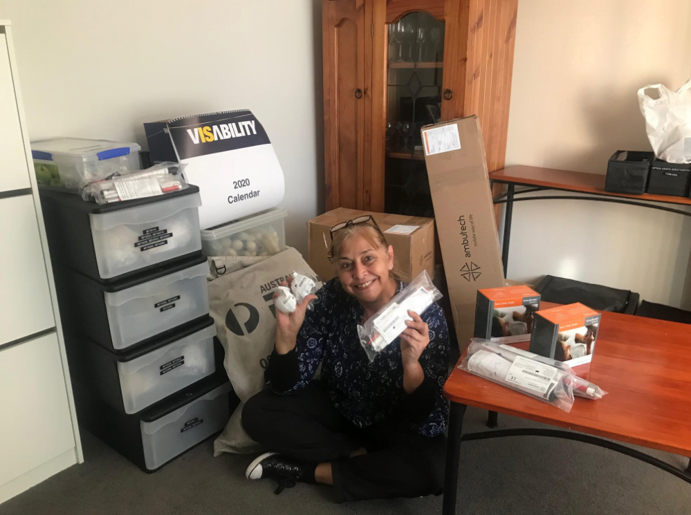 Ivani sits on floor surrounded by some of the VisAbility shop resources including tips of canes