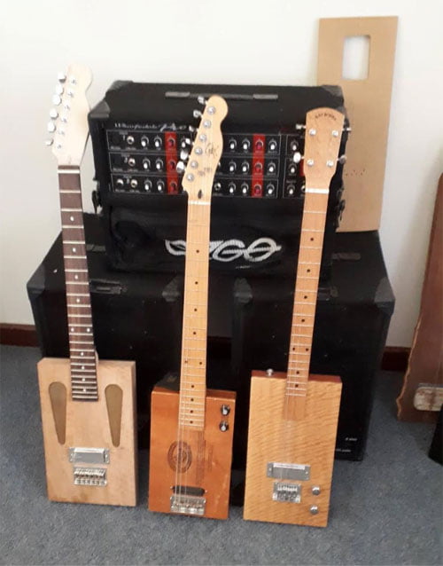 Three box guitars which Les has made lean against a sound speaker