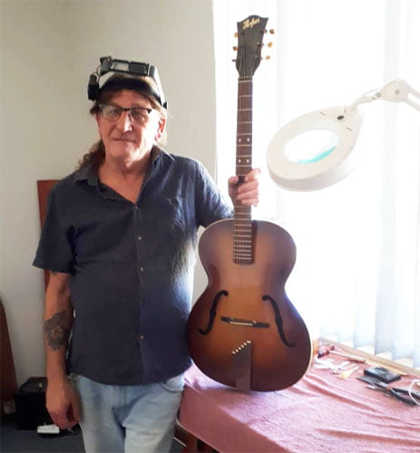 Les stands next to one of his guitars which he has built