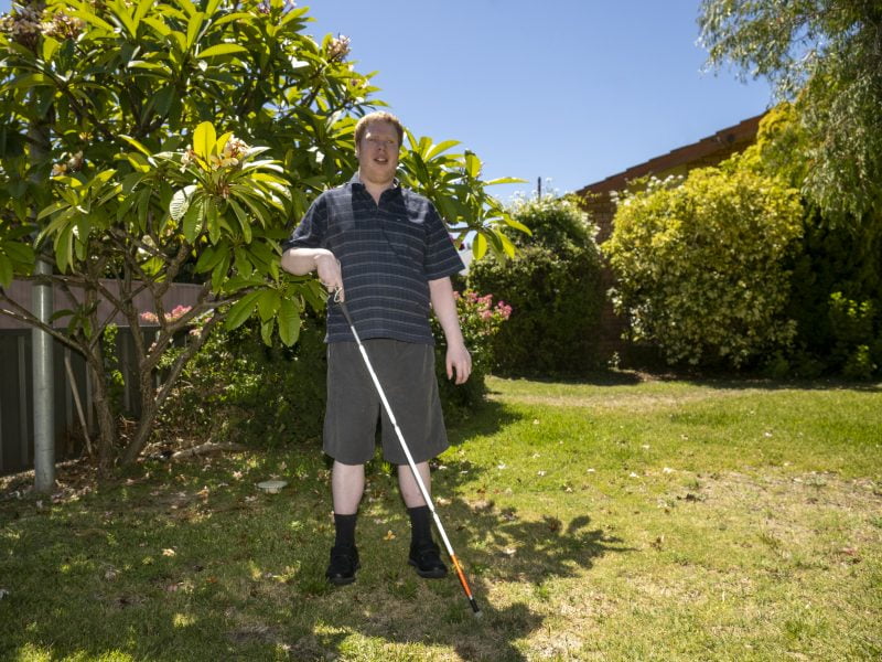 Graham standing in his garden with his white cane
