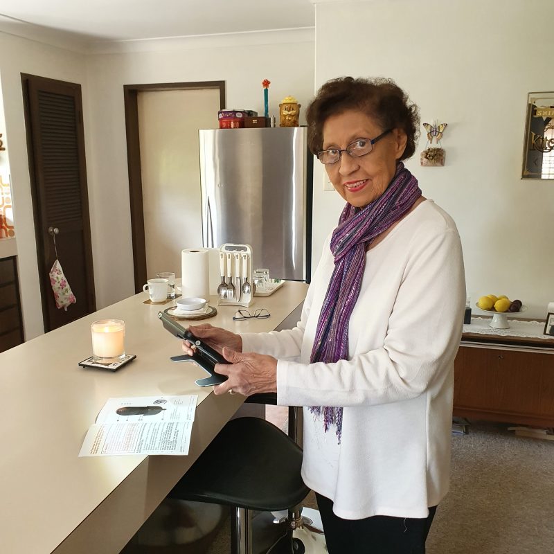 Shirley standing in kitchen holding a video magnifier