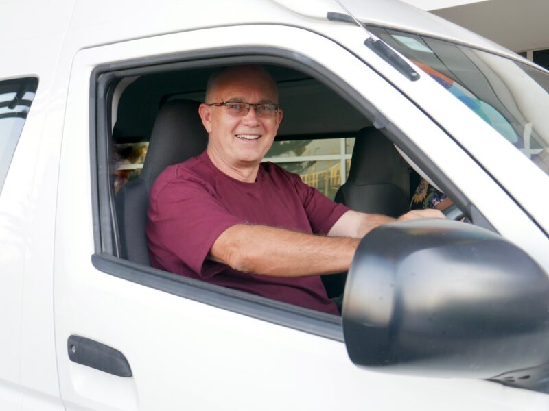 Volunteer driver Graeme sat at the steering wheel of the mini-bus smiling