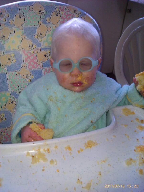Kaleb in a high chair wearing glasses