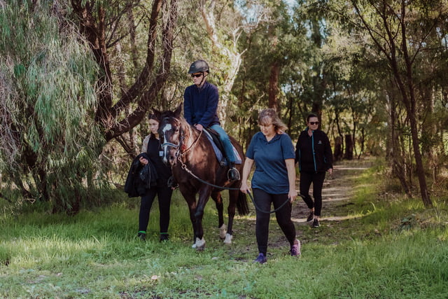 Nicole sitting on her horse being guided by someone else