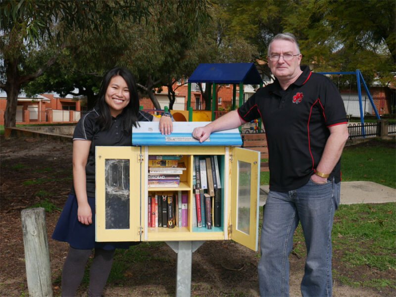 Lee-Ann and her publisher stand next to a book library in Vic Park