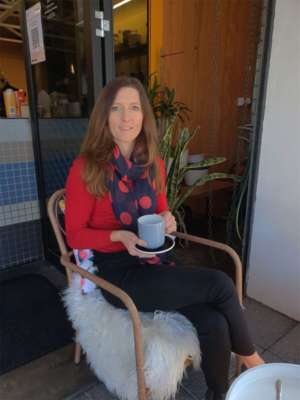 Melanie holds coffee cup in hand in coffee shop 