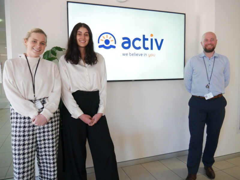 Niall and his team members stand next to a screen that reads Activ