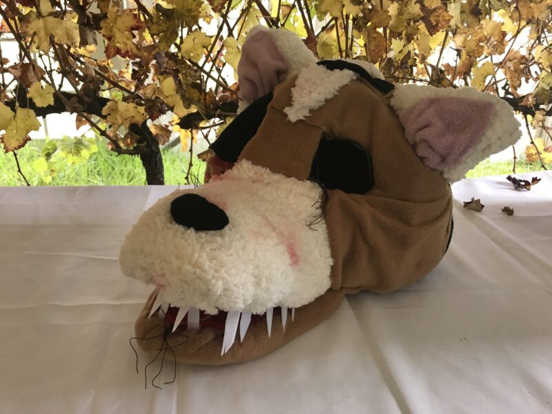 Big wolf like mask with brown and white felt and big nose on wire frame on table 