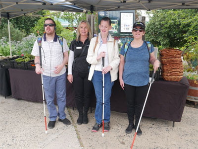 Four people with white canes smile at the camera