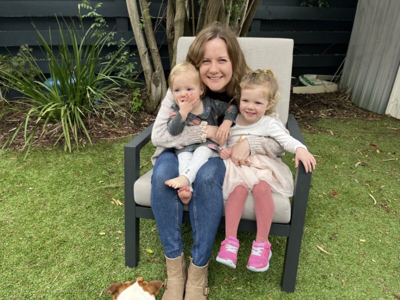 Sinead sits on a chair outside with her children Mary and Mairead