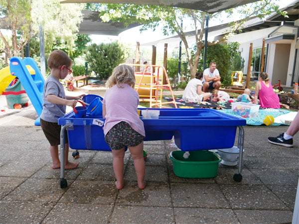 Two young children play with toys in a water play tray in a VisAbility Playgroup session