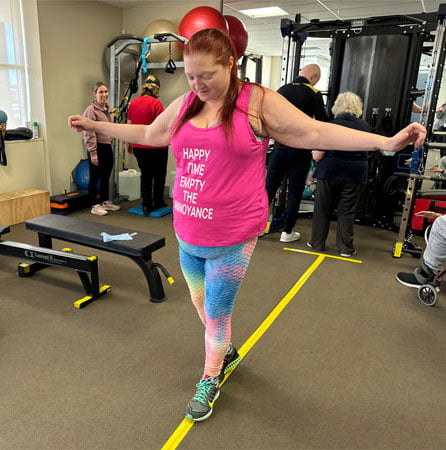 Woman balances while walking along a  line on the floor 