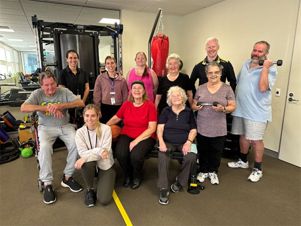 Group of people smiling at the camera in the gym. 