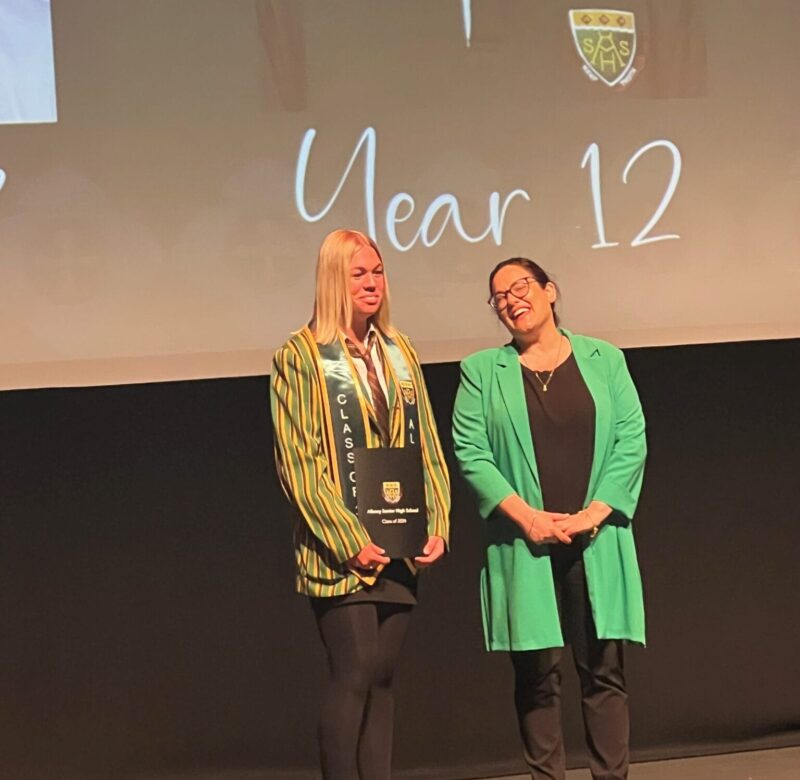 Mikayla Graduating from year 12, standing beside her teacher Tracey Myers.