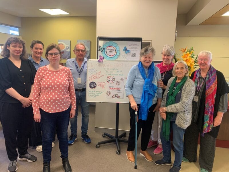 Volunteers stand beside a thank you message board written for national volunteer week.
