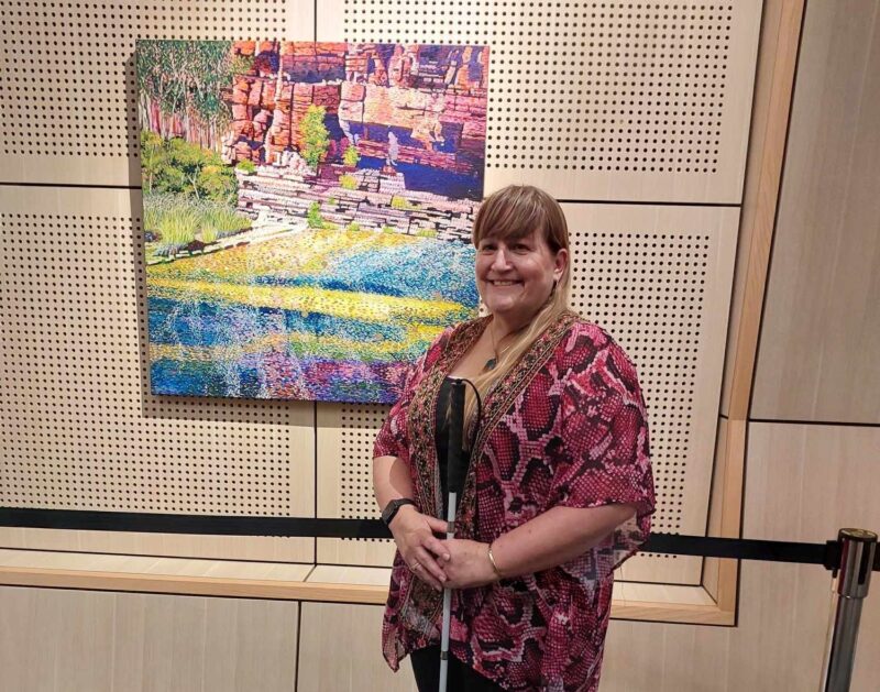 Ericka stands in front of her painting at the AccessAbility exhibition in Karratha
