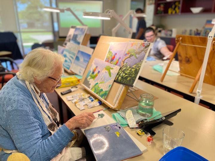 A Community Activity Centre member preparing to start painting an ongoing piece of art.